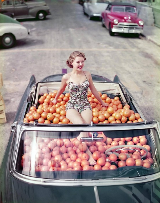 Une femme au milieu des oranges dans une décapotable