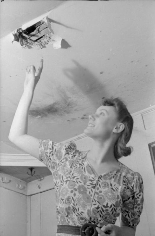 Mrs Olive Day montre un trou dans le plafond par lequel une bombe incendiaire est récemment passée.