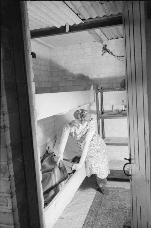 Mrs Olive Day fait le lit de camp placé dans son sous-sol dans lequel elle ira dormir en cas d'alarme de raid aérien.