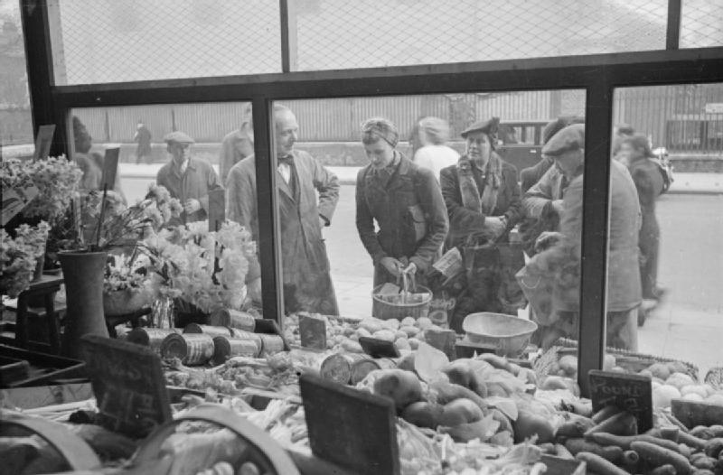 Mrs Olive Day regarde dans la vitrine d'une boutique les produits disponibles.