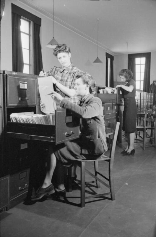 Mrs Olive Day au travail comme secrétaire dans une "organisation reliée à la guerre". Elle travaille en semaine de 10h à 18h et le samedi juqu'à 14h.