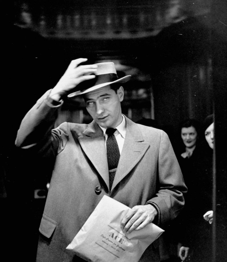 Man setting his hat in place in front of trick mir