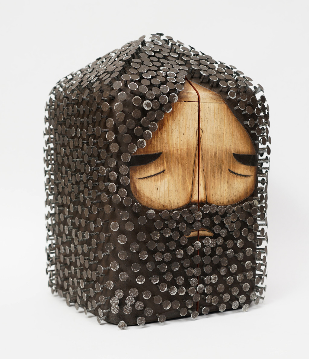 Des sculptures de personnages en tête de bois cloutés